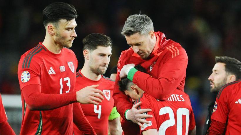Dan James (centre-right) being consoled by his Welsh teammates.