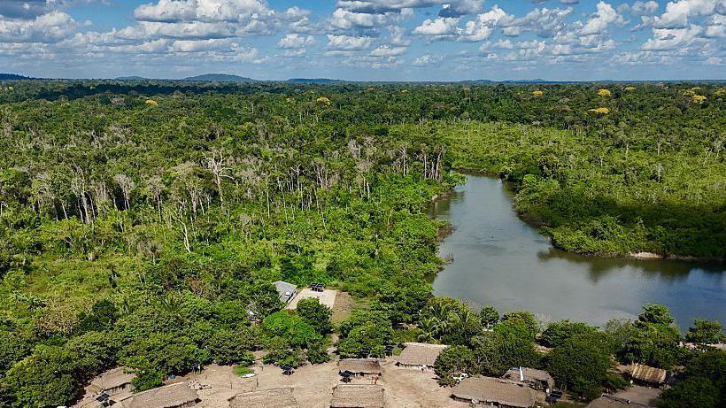 An aerial view of lush green trees and a windy river winding through it, in the indigenous village of Pykany on the banks of Brazil's Xixe River in the Menkragnoti Indigenous Territory, south-western Pará State, in May.