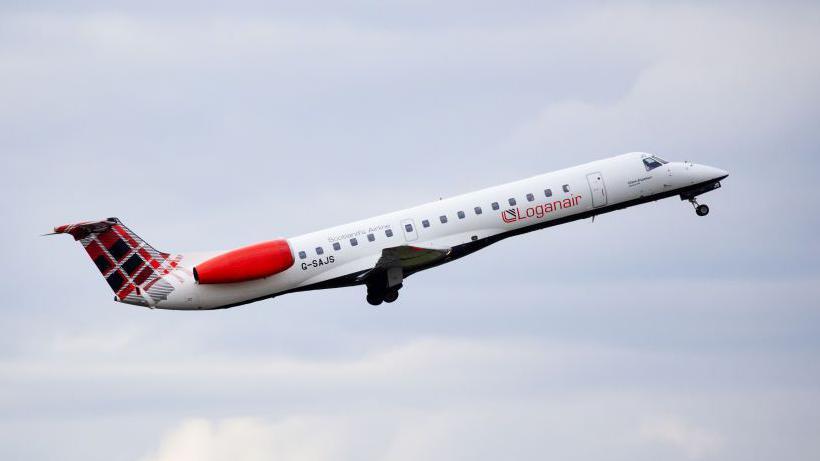 A Loganair plane takes off. It is a small white aircraft with red engines and a tartan design on the tail
