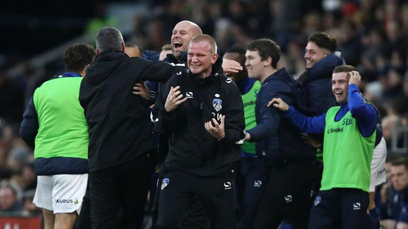 Oldham caretaker manager Pete Wild celebrates victory with staff