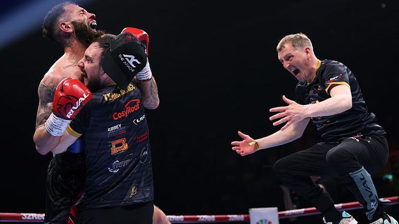 Anthony Cacace is embraced by coaches Barry O'Neill and Michael Hawkins Jr