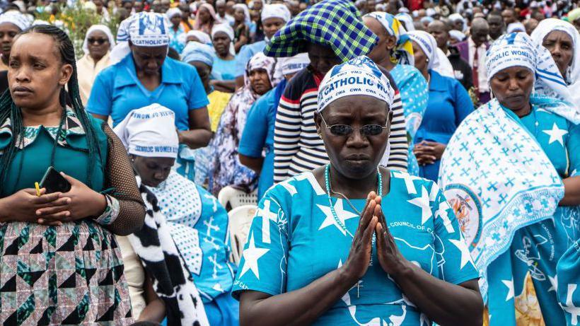 Women with heads bowed and hands held in prayer during an outside mass at the Subukia National Shrine in Kenya - October 2024