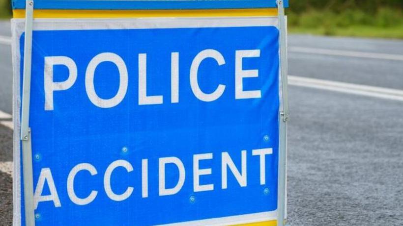 A police accident sign in white on blue next to a road