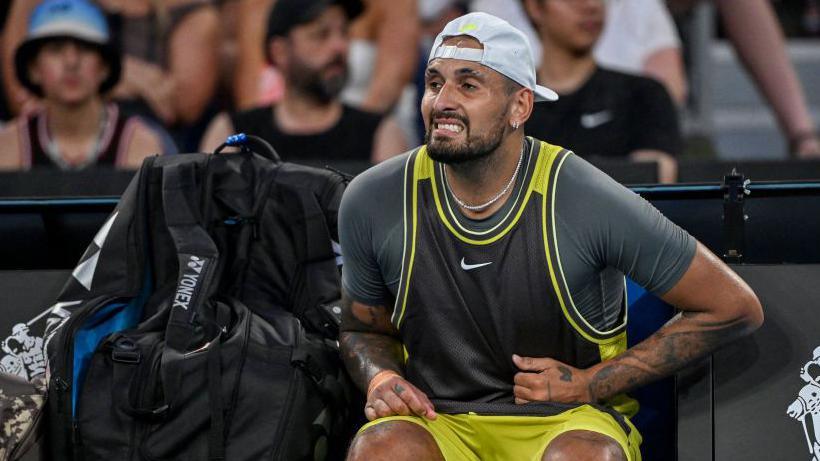 Nick Kyrgios clutches his abdomen area 