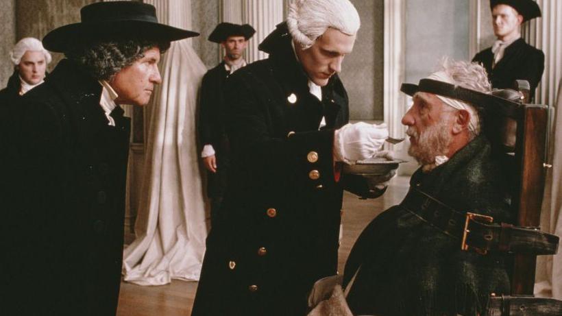 Still from the film Madness of King George, showing the king being fed while strapped into a chair