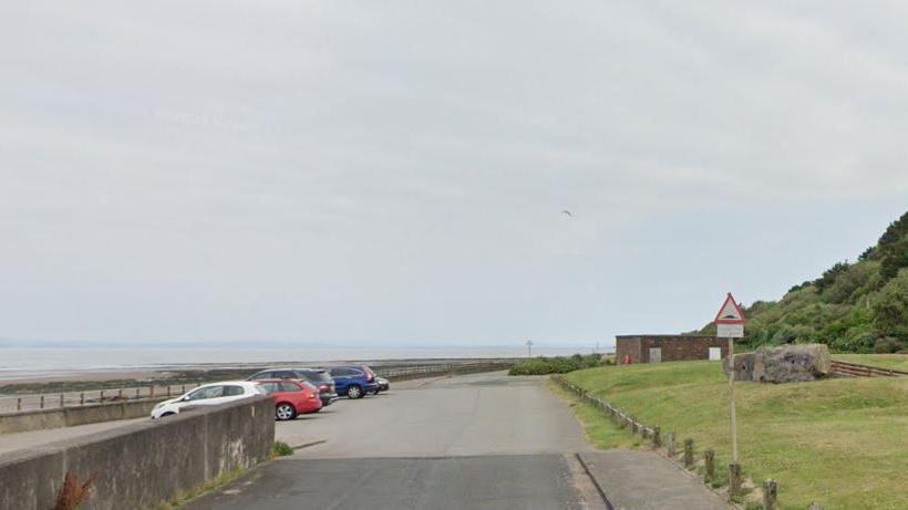 A general view of the area where the skate park will be built. It shows the promenade with cars park along it and a building on the other side of the road