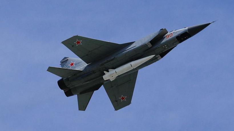 Fighter jet with Kinzhal hypersonic missile on its underside, pictured against blue sky