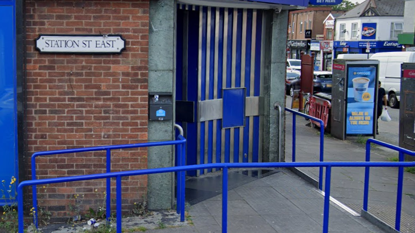 A white sign with a black edge on a brick wall, saying Station Street East