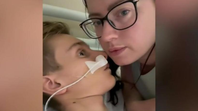 A still from a video showing Jack Dolan with his face close to his mother in hospital. She is looking at the camera.