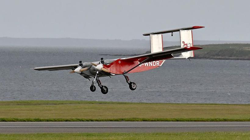 A picture of a fixed-wing drone painted in Royal Mail red landing at Kirkwall, Orkney