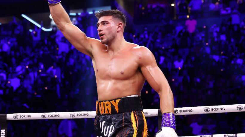 Tommy Fury raises his glove in the air in the ring