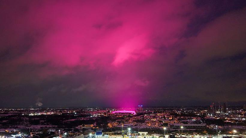 An aerial shot of Birmingham city centre which shows a vivid pink glow, coming from the St Andrew's football ground, being reflected off clouds above it, sending the whole sky pink