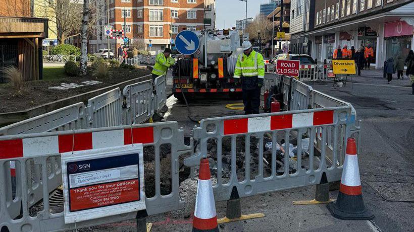 Engineers in hi-vis jackets carrying out repair works to gas pipes.