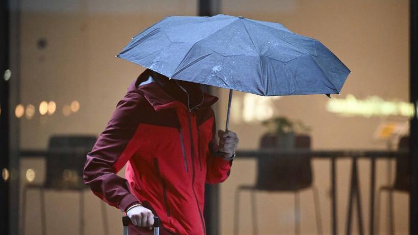 A person in a red coat holding an umbrella