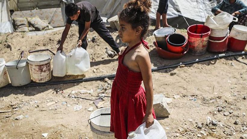 A displaced Palestinian girl holding plastic buckets to collect water in a temporary shelter in Gaza City on 20 May 2025.