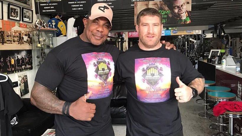 David Lawrence when he was bodybuilding, with Matty Hudd at Trojan Fitness gym smiling at the camera with their thumbs up