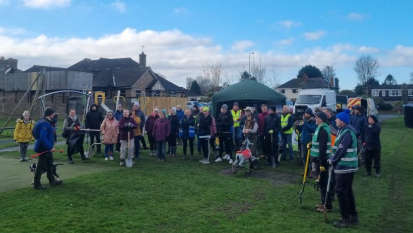 A large group of people with spades ready to begin planting the trees