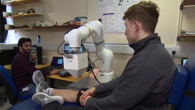 A man in a lab with his trouser leg rolled up