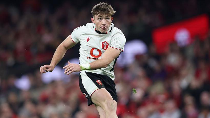 Dan Edwards swings his leg and holds his arms to the side as he kicks the ball off a tee during a Test match for Wales this autumn