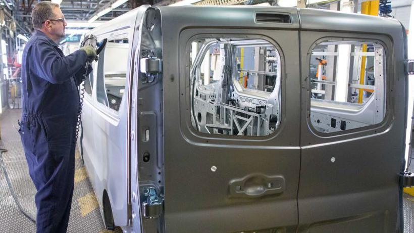 An employee smooths the edges of a window panel on a Opel Vivaro medium sized van in the bodyshop at the Vauxhall plant in Luton.