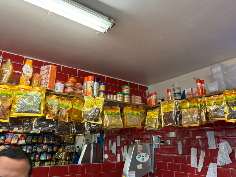 Inside a butcher's shop in Southwark, London packets of spices hang from a shlef on top of which are bottles and containers of illegal skin whitening products