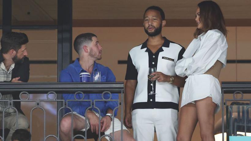  Nick Jonas (C-L) speaks with John Legend and Chrissy Teigen as they attend the Artistic Gymnastics Women's Qualification