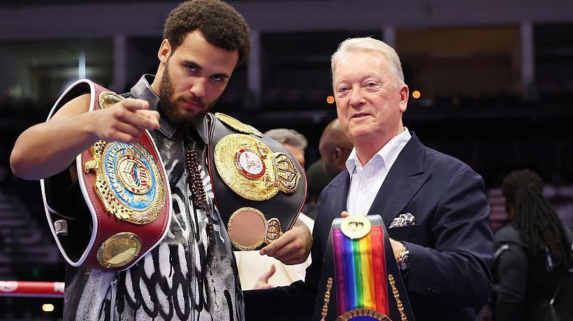 Moses Itauma poses with his belts beside Frank Warren