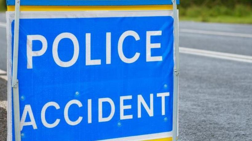 A police accident sign in close up in front of a road sign