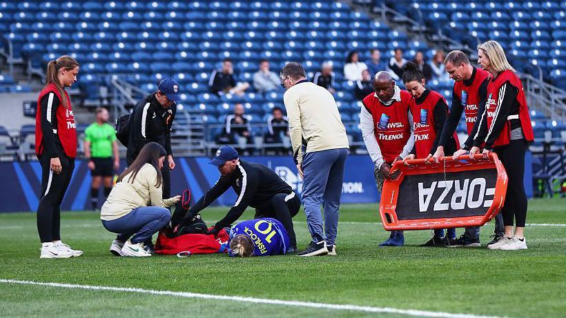 Jess Fishlock is treated on the pitch during Reign's game against Utah Royals 