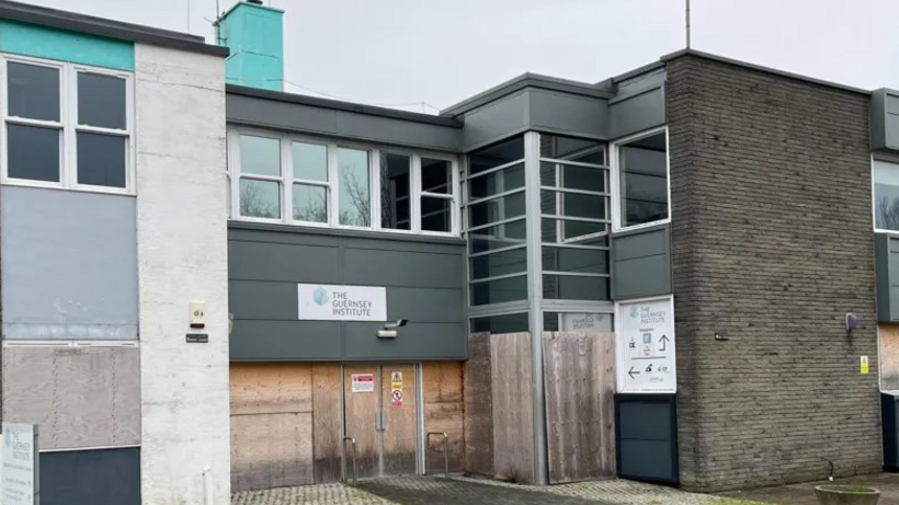 A building which has a sign saying "The Guernsey Institute" written on it above some doors which appear to be boarded up.