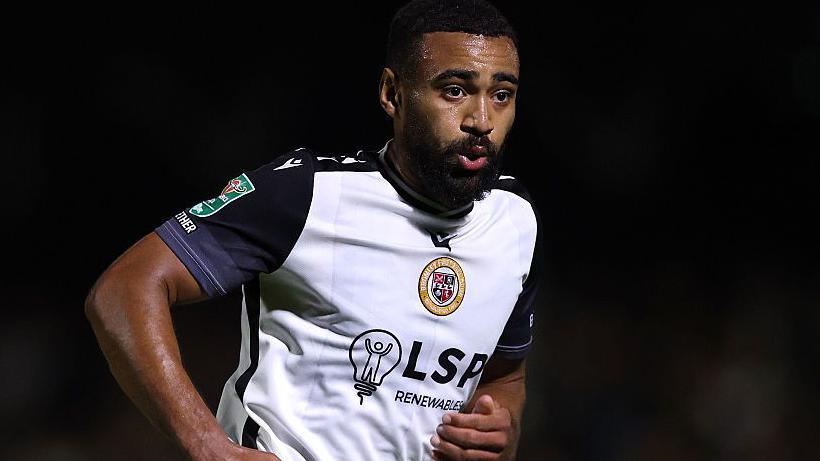 Ashley Charles, wearing a white shirt with black sleeves, in action for Bromley