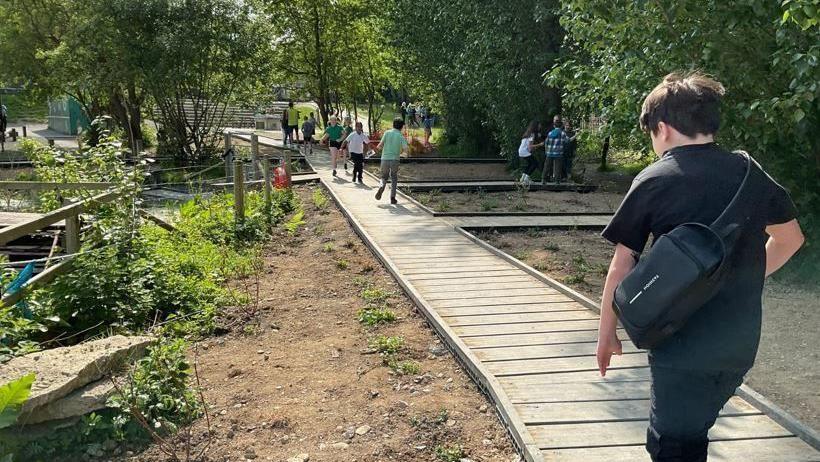 Plant yn cerdded ar lwybrau pren yng ngardd Ysgol Plascrug yn Aberystwyth 