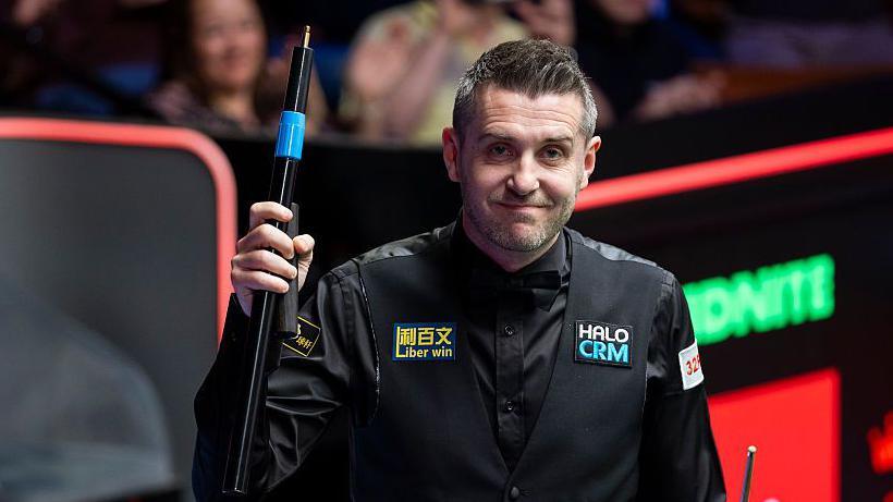 Mark Selby raises his extension and smiles