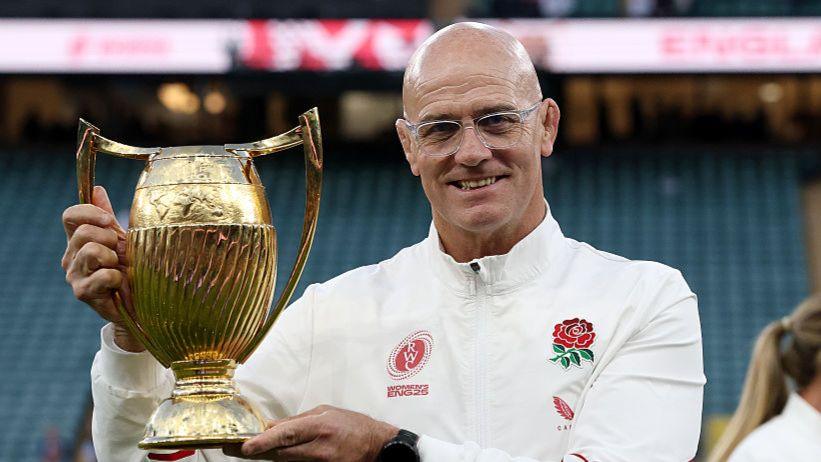 John Mitchell holds up the World Cup