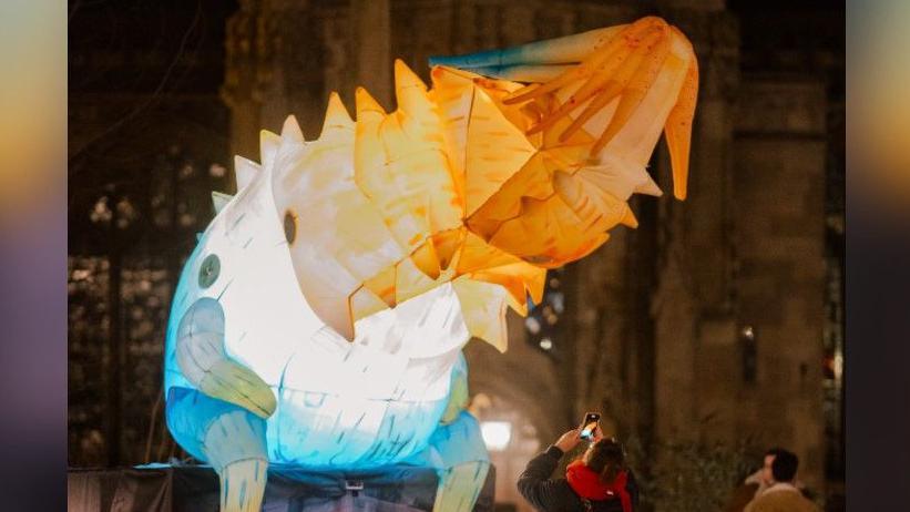 An air giants mystical light creature, of part sloth, spirit and dragon, which is lit up and blue, white and orange in colour.