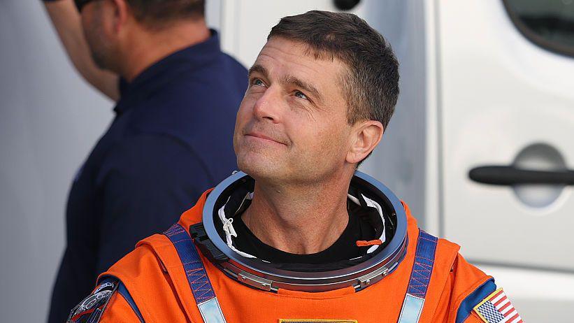 Reid Wiseman looking to the left wearing an orange spacesuit