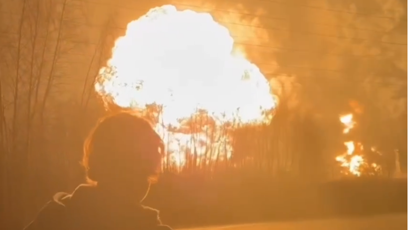 A man stands in the foreground as a fireball erupts at the Ryazan oil refinery