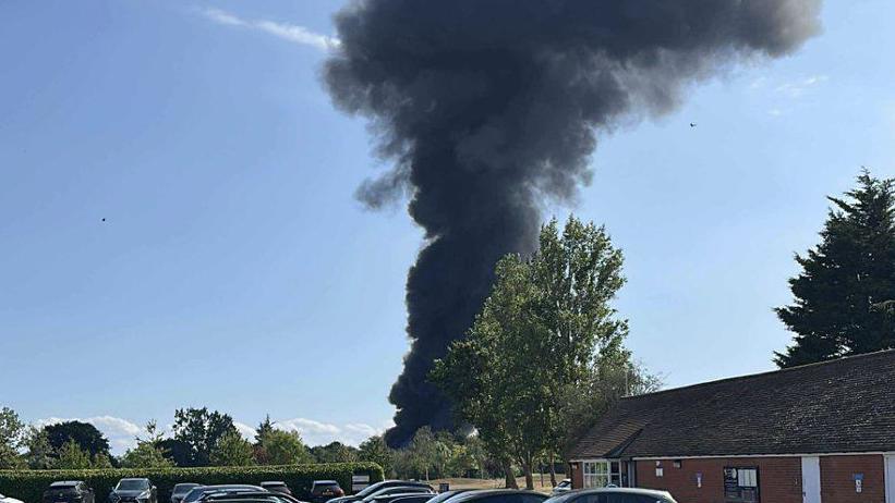 Thick dark smoke is billowing into the blue sky from the incident - which cannot be seen in the image.
