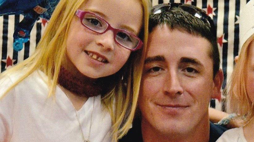 Photo showing young girl with blonde hair and glasses, beside an older man with black hair and sunglasses on his head.