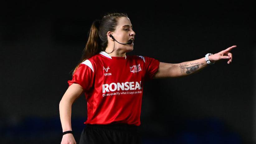 Referee Tara Jones speaking into her microphone attached to her ear while pointing towards a player while in charge of London Broncos v Widnes Vikings.