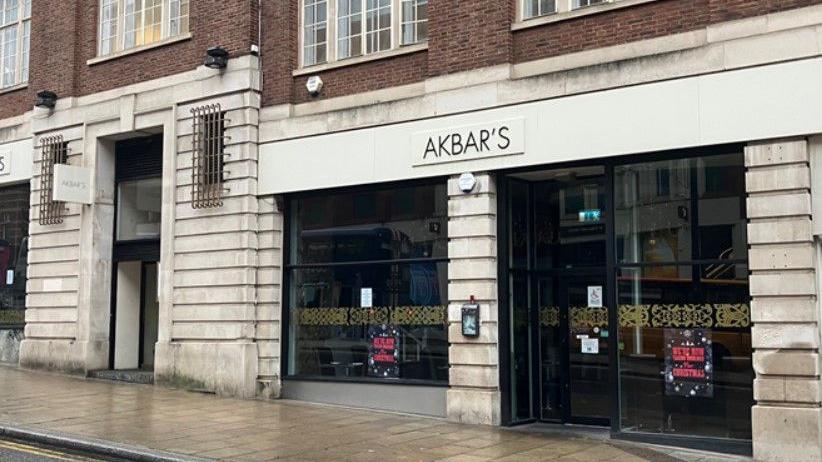 A restaurant front bearing the name Akbar's. The glass-front entrance is split by a stone pillar.