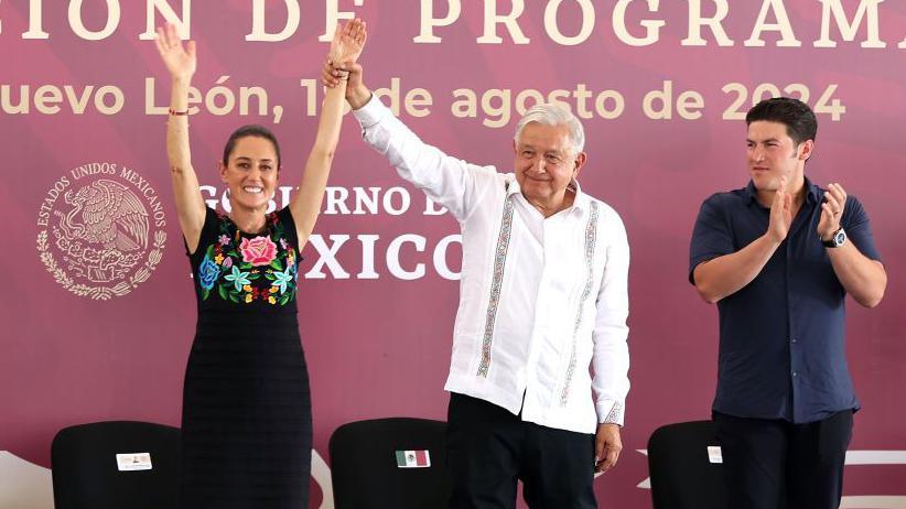 Andrés Manuel López Obrador holding up Claudia Sheumbaum's arms at an event back in August