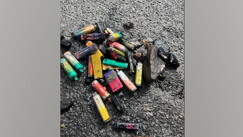 A pile of dirty vapes on a road.