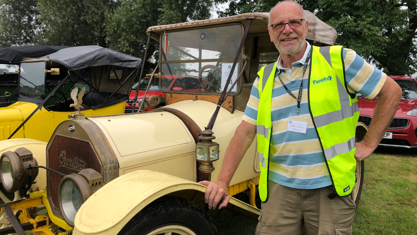 Robert Hadfield in a hi-vis jacket standing by a classic car