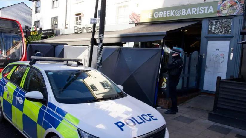 A police car parked outside a restaurant in Chelmsford and the entrance has been covered up.