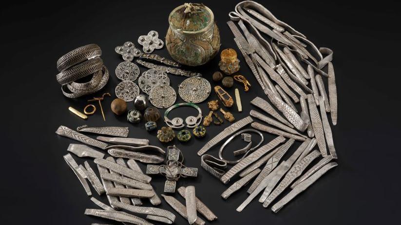 A collection of metal objects, including brooches and bracelets, displayed against a black backdrop.