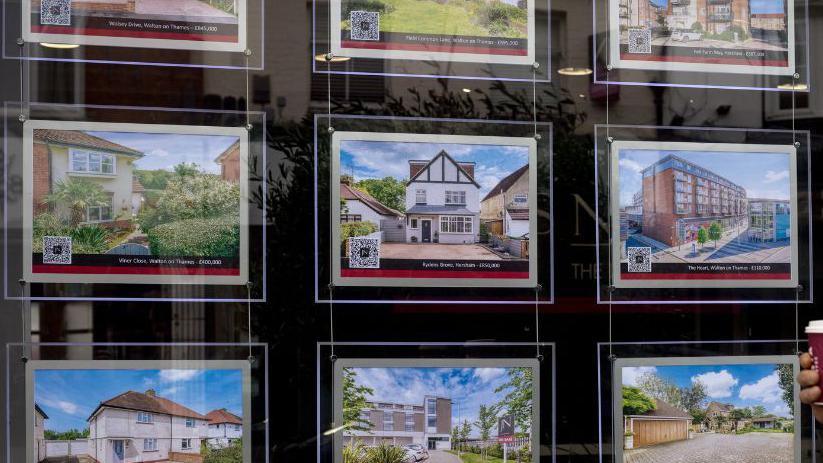 Man walks past a display of properties in an estate agent's window in Walton-on-Thames