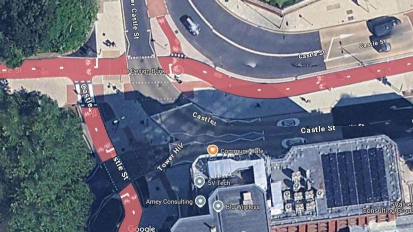 A google street aerial snap showing a road system in Bristol with a red cycle lane through it.