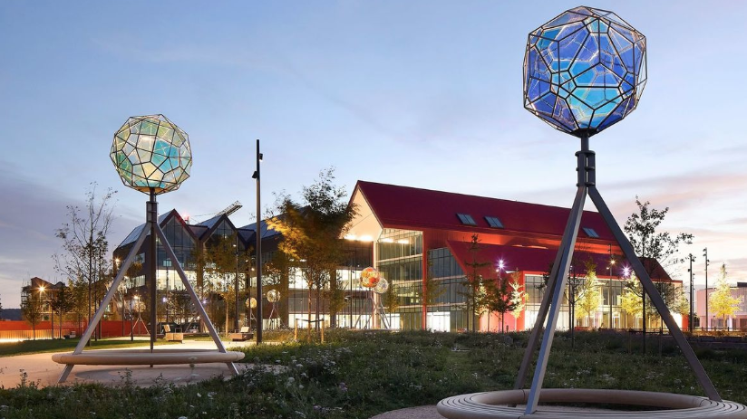 Two large spherical glass and metals sculptures have been mounted on metal tripod stands.  One is pale green, the other blue.  They are lit from inside.