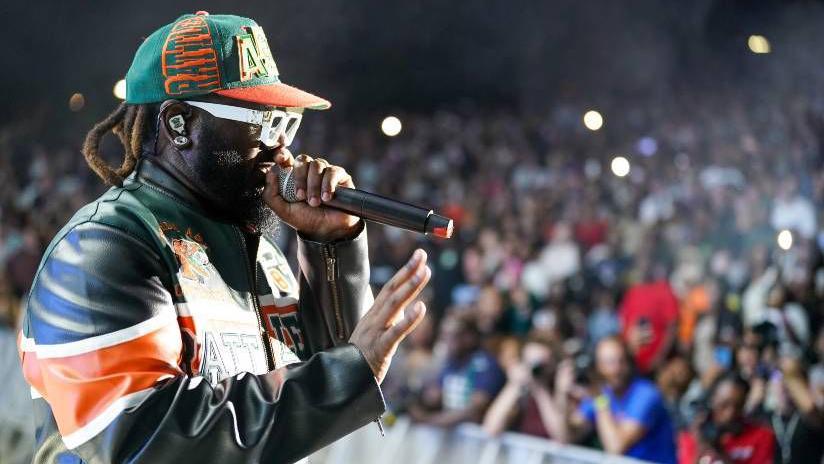 T-Pain, pictured wearing a colourful leather jacket, white sunglasses and a green and orange baseball cap, performing in Florida last weekend